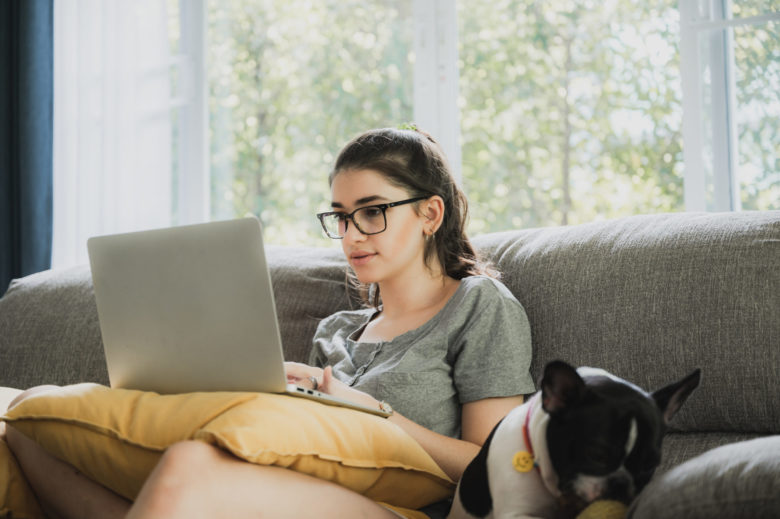 Funny and cheerful girl watching comedy movie on laptop with spectacles and pet dog