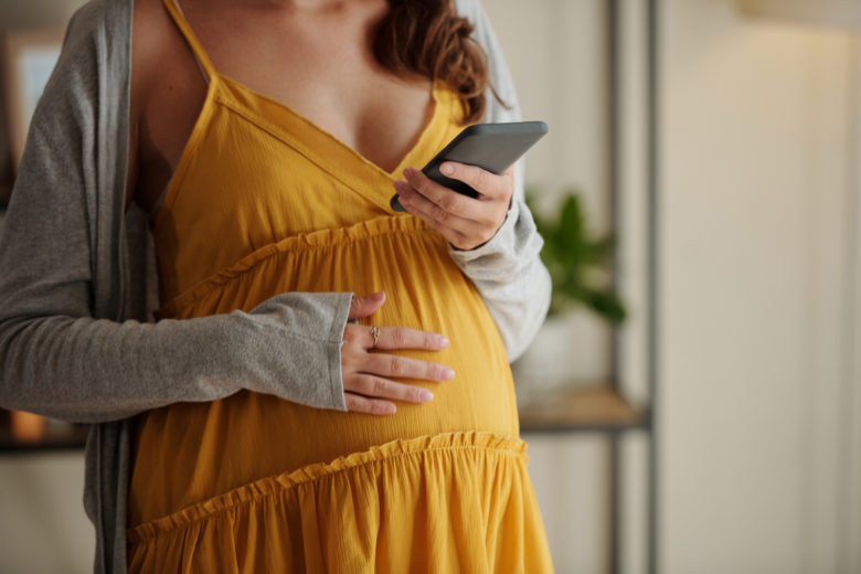 Pregnant woman getting message on her mobile phone
